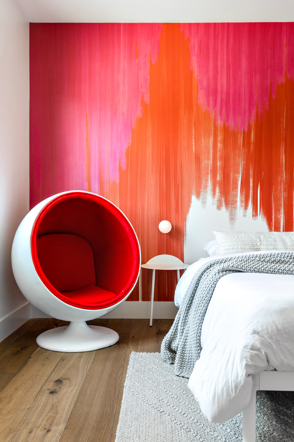 Iconic Design + Build bedroom with red and orange painted wall with red orb chair