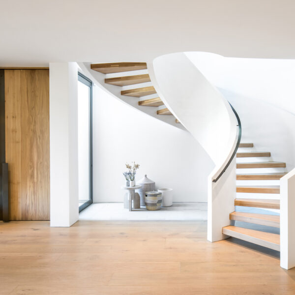White curved staircase naturally lit from above. RED Winner