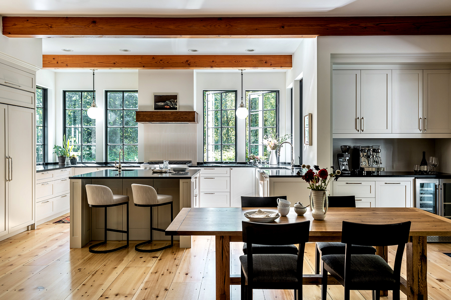 An open concept kitchen stretches across a clean white wall with wooden beams overhead. RED Winner.