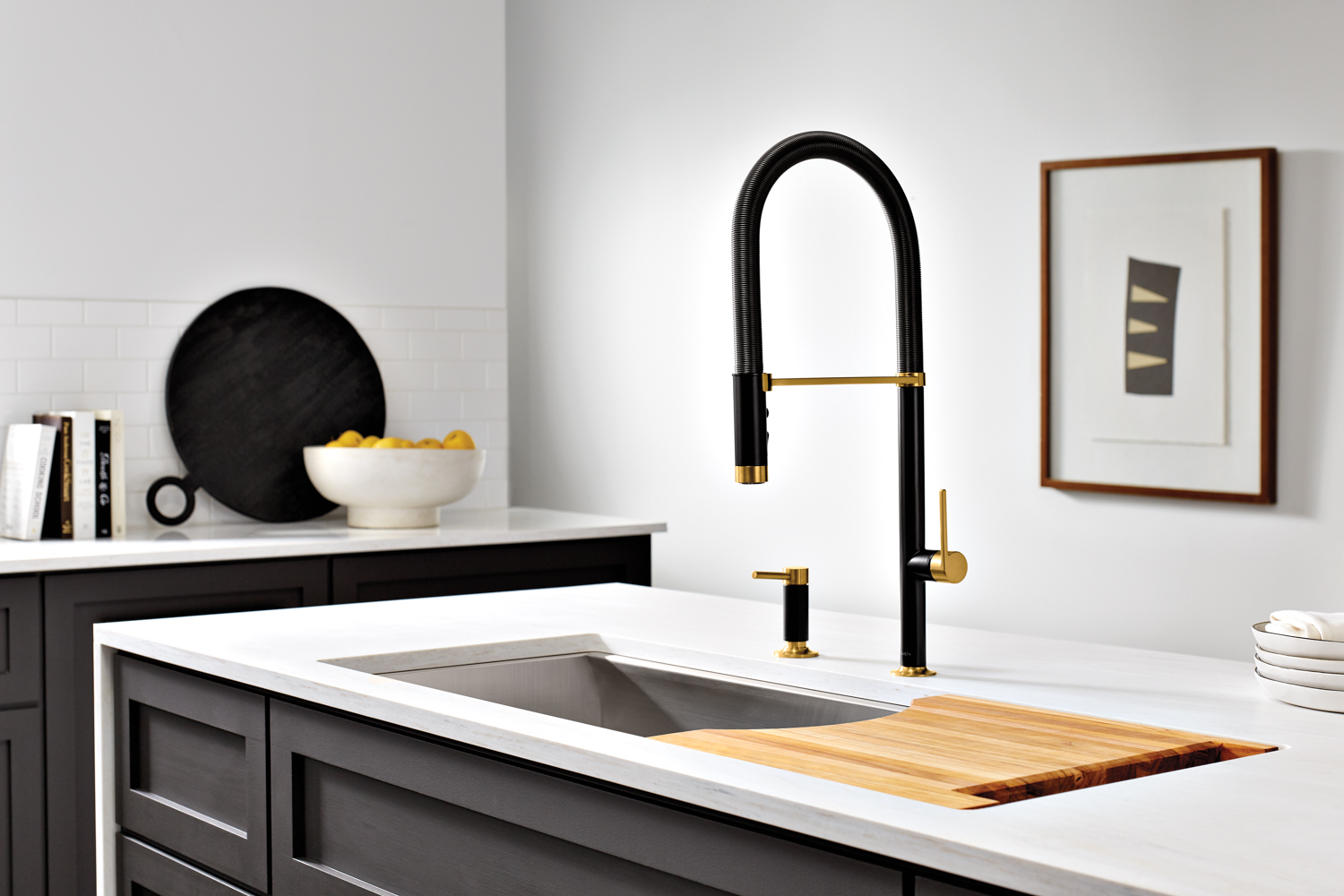 A black metal gooseneck faucet with gold accents in a modern black and white kitchen. RED Winner.