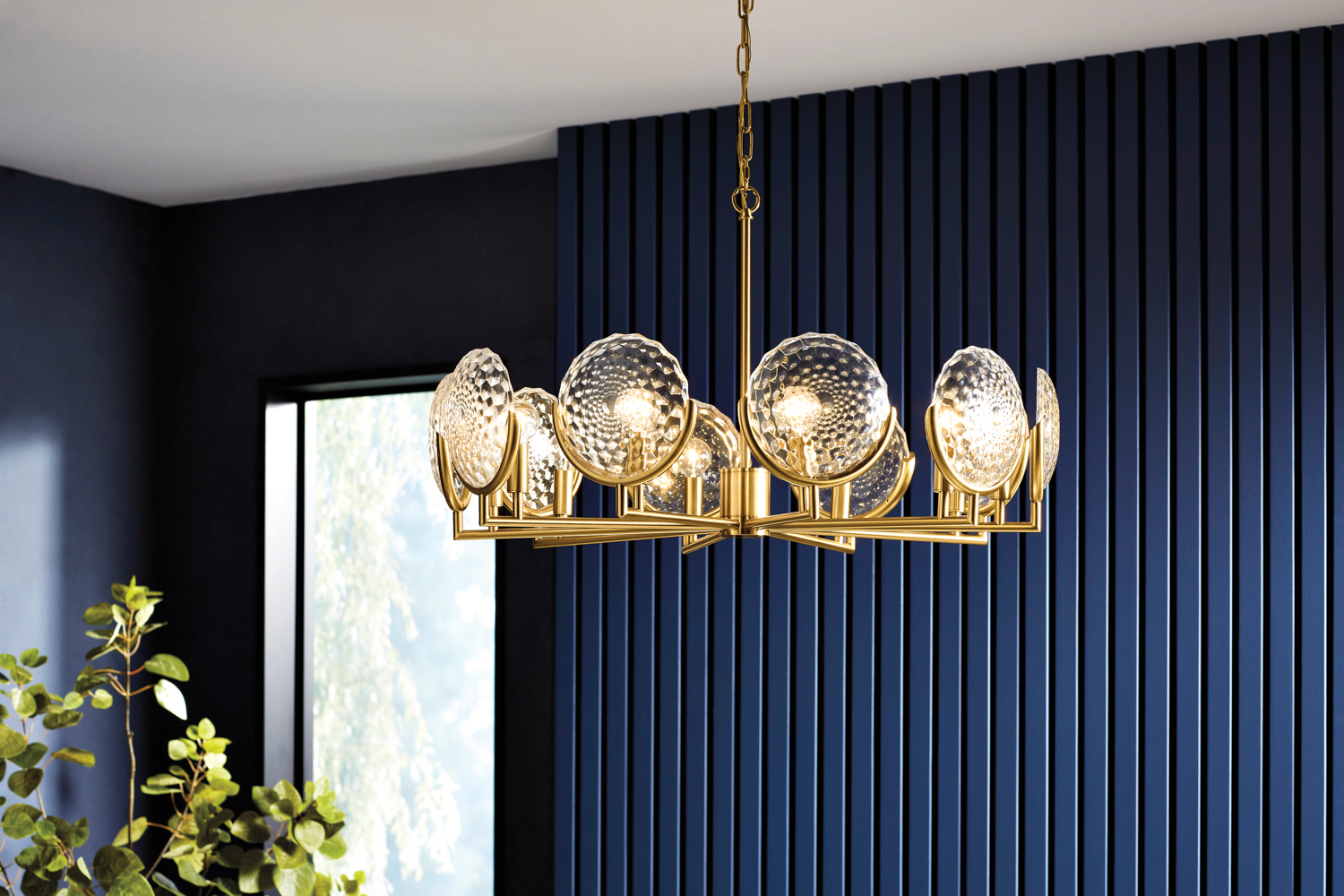A gold chandelier with cut glass accents in a navy blue room. RED Winner.