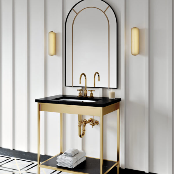 Two minimalistic gold scones flank an arched mirrow over a pedestal sink. RED Winner.