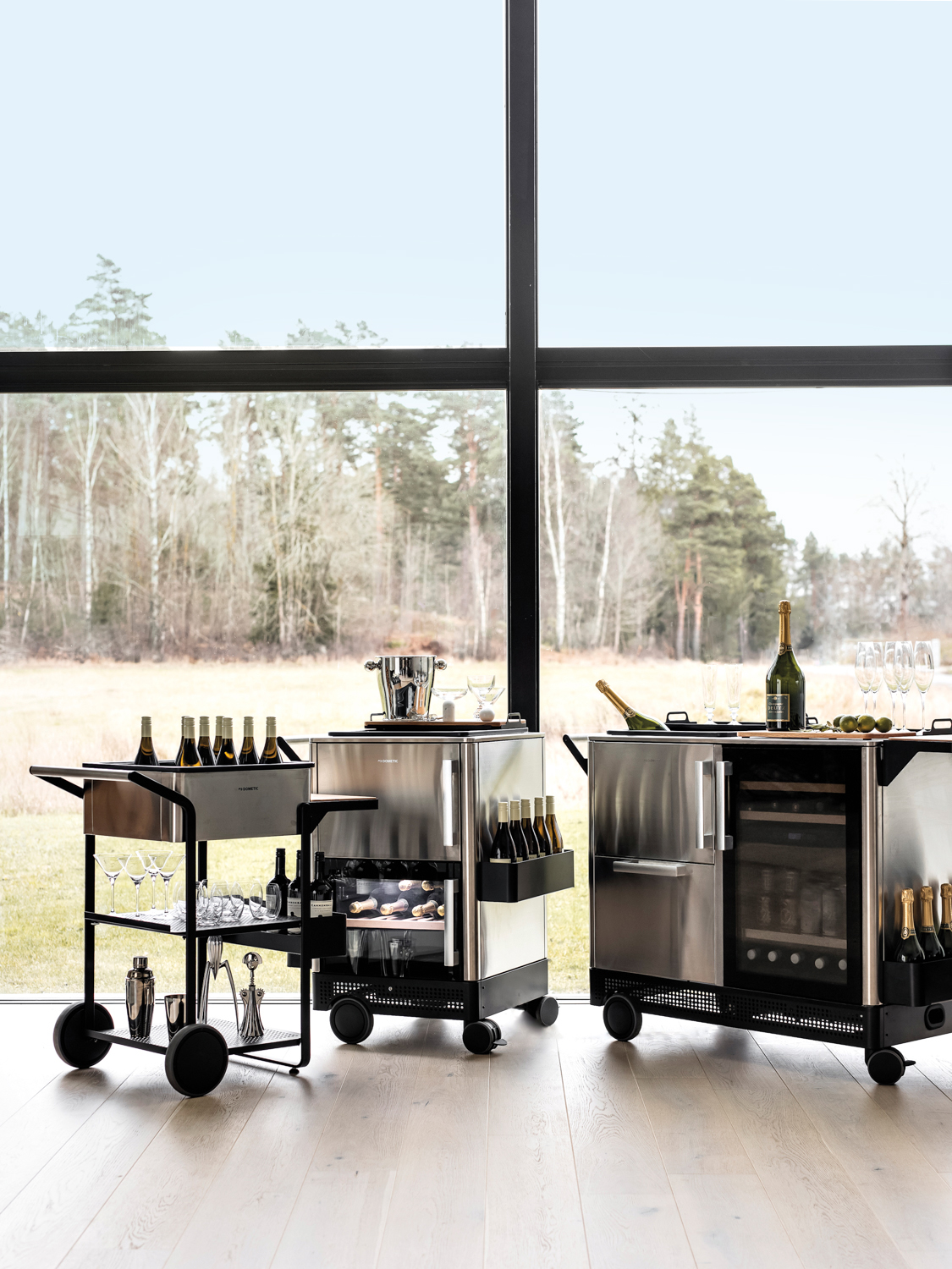 Three different stainless steel bar carts sit in front of an expansive window with nature views. RED Winner.