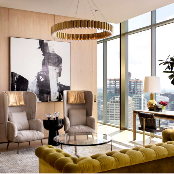 A gold toned living room with velvet furnishings and floor to ceiling views of the Austin skyline. RED Winner.