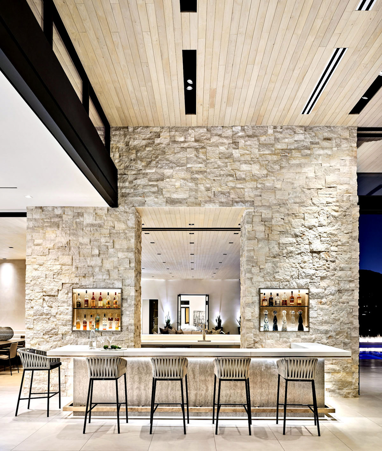 Modern Bar area against a natural limestone wall with dramatic uplighting. RED Winner.