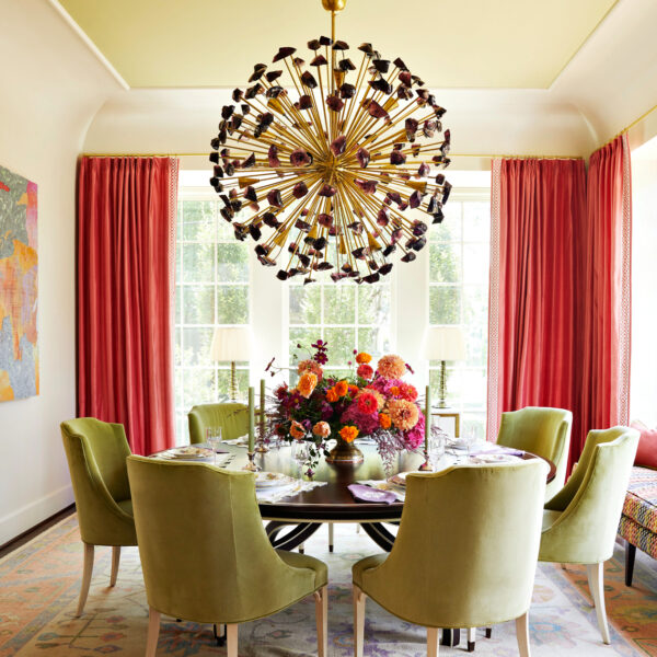 Green velvet chairs encircle a round table set with candles and florals. RED Winner.