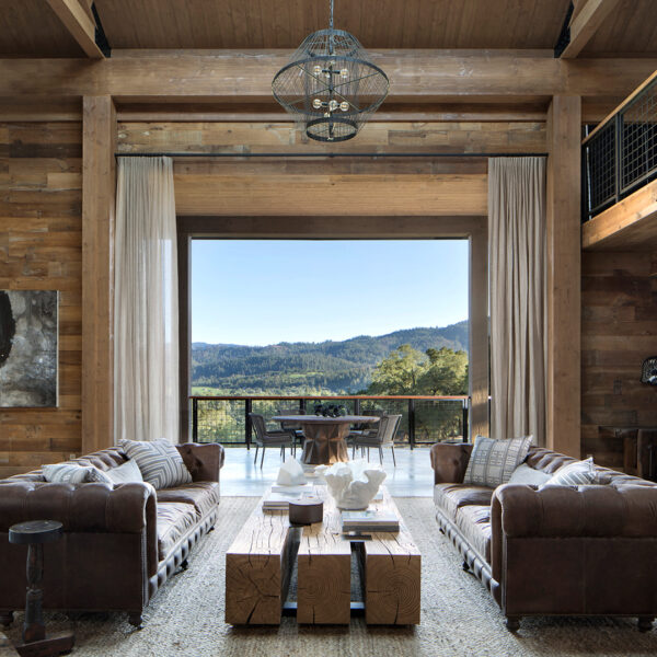 A wooden living room with leather sofas oepns up to an expansive outdoor patio. RED Winner.